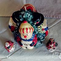 Front view of large singing snowmen candle with two Santa Claus figurines in front