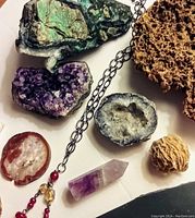 Overview of lot showing turquoise mineral, amethyst geode, blue-gray small geode, desert rose fossil, amethyst crystal point, coral, agate slice, ammonite fossil, and beaded necklace.