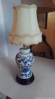 Full view of the vintage blue and white Chinese porcelain boudoir lamp with cream fabric shade.