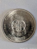 Obverse side showing 'CANADA 1864-1964 DOLLAR' with floral emblem and central cross design labelled 'CHARLOTTETOWN QUEBEC'.
