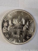 Obverse side of the 1963 Canada silver dollar coin showing the voyageur canoe design, year 1963 and inscriptions.