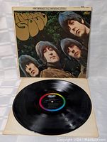Photo showing Rubber Soul vinyl record partially removed from cover, displaying Capitol label with colorful rings and vinyl grooves.