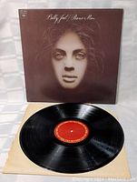 Photo of Billy Joel Piano Man vinyl record LP out of its sleeve showing red label and the vinyl surface.