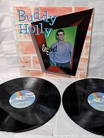 Front view of Buddy Holly 'Legend' album cover with two vinyl LPs laid out showing record labels and vinyl condition.