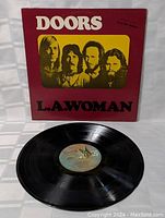 Front cover of The Doors L.A. Woman record showing band photo in yellow square on red background with title and band name.