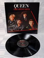 Front view of Queen Greatest Hits vinyl record and cover showing band photo and title.