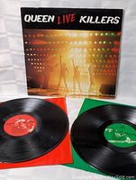 Two vinyl records included, one with red label and one with green label on respective inner sleeves.