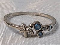 Close-up of sterling silver ring showing starfish design and aqua blue stones on a textured surface.