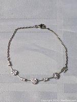 Full view of the sterling silver bracelet laid flat on textured fabric surface.