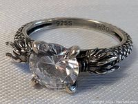 Close-up view of the sterling silver ring with detailed dragon claws holding a large clear crystal, showing 925S mark inside.