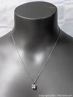 Necklace displayed on black bust showing pendant and chain length.