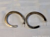 Photo showing both sterling silver modernist hoop earrings, highlighting their shape and shiny surface.