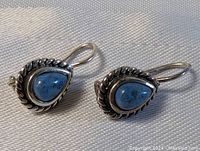 Front view of the pair of sterling silver earrings with blue stones.