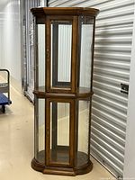 Full view of two-tier wooden curio cabinet with bowed glass panels and wooden frame.