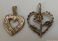 Two pendants side by side: tri-coloured gold woven heart pendant and gold heart with rose flower pendant.