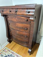 Angled front view showing convex drawer fronts, wood knobs, scrolled side supports and bracket feet