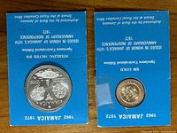 Two blue cardboard holders displaying the $10 and $20 anniversary coins