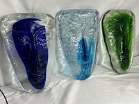 Group shot of all three glass face sculptures in cobalt blue, light blue, and green