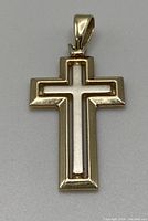 Front view of two-tone cross pendant on gray background