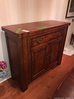 Front view of wooden Century sideboard showing drawer and double cabinet doors with metal handles, medium brown finish wood.