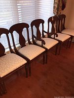 Six Lexington dining chairs arranged in a row showing wood curved backs and upholstered seats in light patterned fabric.