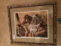 Framed print of a Native American chief standing with a horse, showing full view of framed artwork on wall.