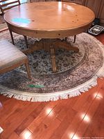 Full view of round area rug under a wooden dining table and chairs to show size and shape.