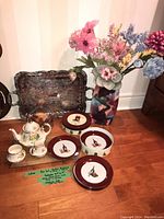 Lot showing Sadler tea set pieces grouped on floor with Happy Hour plates, silver plated tray behind, and Mikasa vase with faux flowers on right.