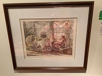 Framed print showing full view of the artwork including frame, depicting woman holding baby in a floral chair inside a sunlit room.