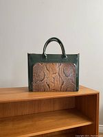 Front view showing green leather body with snake skin panel pocket and leather top handles