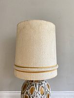Full view of the mid-century modern textured off-white lamp shade mounted on a ceramic base for scale and appearance showing minor staining.