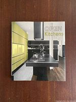 Front cover of the book showing a modern kitchen with bright yellow-green cabinetry and a central island with a stovetop and stainless steel range hood.