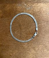 Full view of the sterling silver bracelet laid flat on a wooden surface showing the entire chain and clasp.
