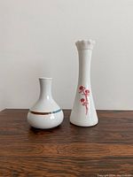 Two vintage ceramic table lamps on a wooden surface against a plain wall, showing front view with decorative patterns