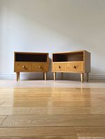 Front view of two wooden vintage nightstands side by side on wooden floor against white wall