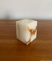 Front view of the white onyx cube candle holder with natural brown veining on wooden surface.