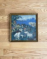 Full view of the framed embroidered artwork depicting a woman and child with sheep in a pastoral setting.