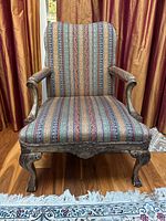 Front view of the antique French style armchair showing carved gilt-finished wooden frame and patterned upholstery with striped fabric and down-filled cushion
