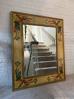 Full view of the antique style wooden wall mirror showing the entire golden frame with painted floral details and the reflective glass.