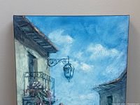 Close-up of canvas print showing upper portion with balcony, street lantern, and blue sky with clouds.