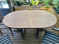 Front view of oval teak table with slatted top and dual pedestal bases