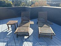 Two teak lounge chairs side by side with matching side table on deck