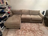 Angled view of sectional sofa with chaise on left next to shelving unit