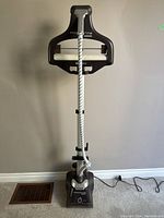 Full front view of Rowenta standing garment steamer showing integrated hanger, steam hose wrapped around pole, and base unit on floor with power cord unplugged.