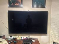 Front view of the Samsung plasma TV mounted on the wall with visible screen and items underneath.