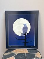 Framed signed print showing an eagle perched on a tree branch with a full moon in the background. Print has a blue color scheme with Indigenous art style elements.