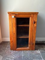 Front view of small pine cabinet with glass door and porcelain knob