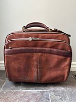 Front view of the cognac leather business case showing zippered compartments and top handle.