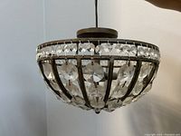 Close-up photo of the bowl-shaped chandelier highlighting the wrought iron frame and crystal details.