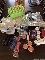 Overview photo showing all items on a dark wooden table including air compressor, flashlights, candles, fan cleaners, green plastic basket, reusable bags, and candle accessories